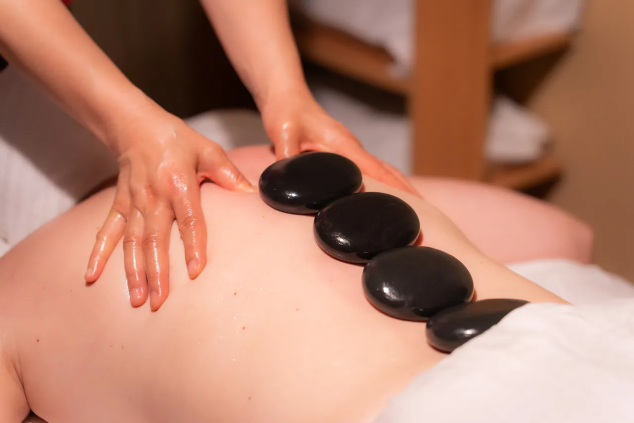 Therapist using smooth hot stones during a back massage